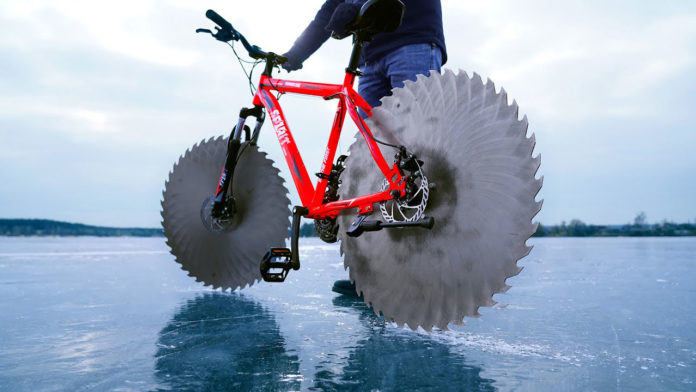 An engineer replaces wheels on a bike with circular saws to ride on frozen lake.