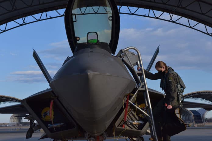 Maj. Nichole Ayers, 27th Fighter Squadron assistant director of operations and F-22 Raptor mission commander, removes a cover from the cockpit of an F-22.