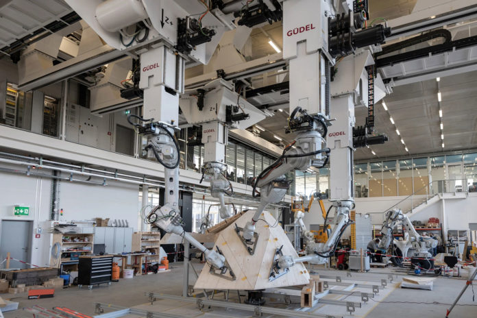 During the creation of the sculpture, four robotic arms pick up wooden boards in unison and place them in space according to the computer design.