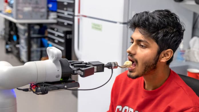 Doctoral student Rajat Kumar Jenamani, a member of Tapomayukh Bhattacharjee’s EmPRISE Lab, prepares to take a piece of a banana from an assistive robot prototype.