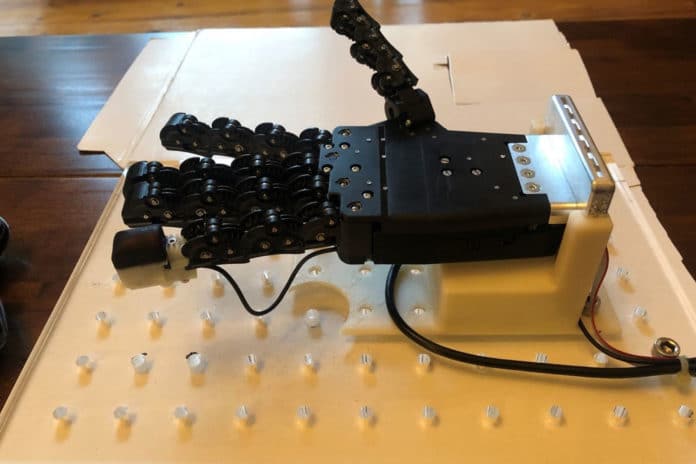 Robotic hand with a 3D-printed tactile fingertip on the little (pinky) finger. The white rigid back to the fingertip is covered with the black flexible 3D-printed skin.