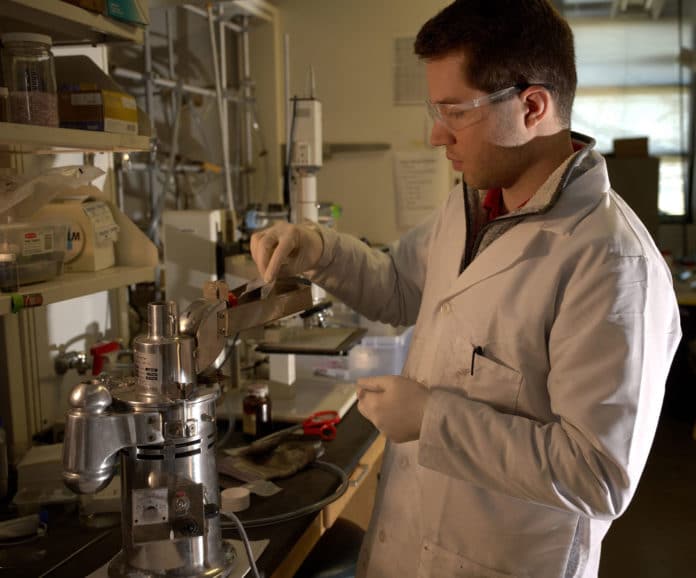 Graduate student Paul Savas feeds raw plastic into a crusher to prepare it for pyrolysis, or heating in an inert atmosphere.