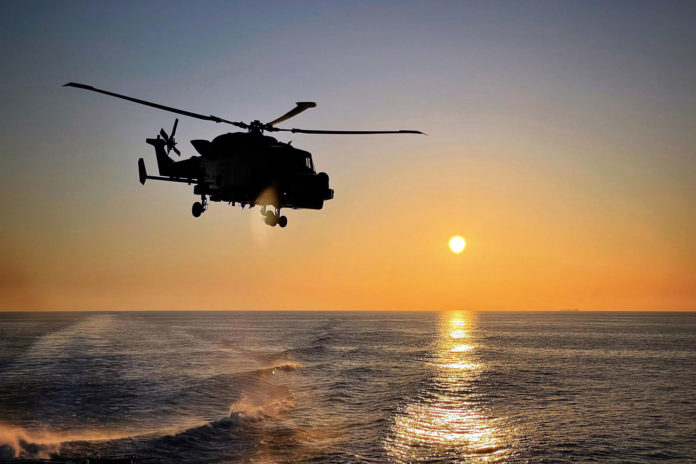 Wildcat helicopter is silhouetted against the setting Med sun.