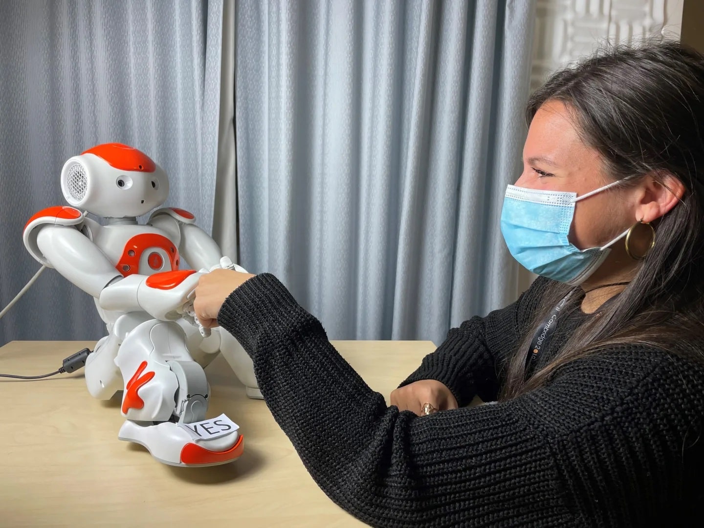 Co-author Dr Micol Spitale shaking hand with Nao humanoid robot.