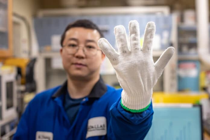 Zhong Wang PhD’21 displays a glove into which he sewed twistron fibers.