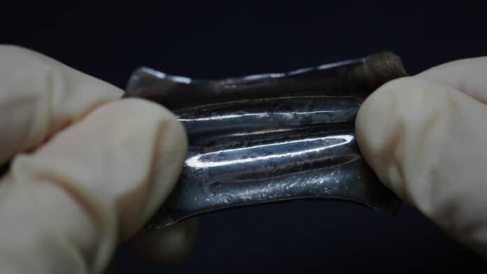 Stretchable battery which is packed in liquid metal is strained by hands.