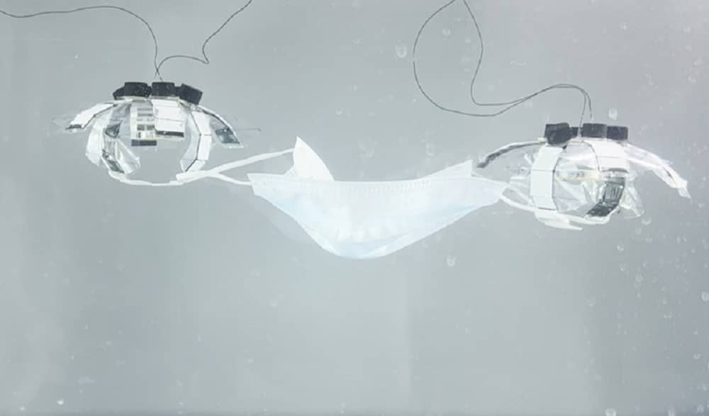 Two jellyfish-inspired underwater robots are picking up a face-mask.