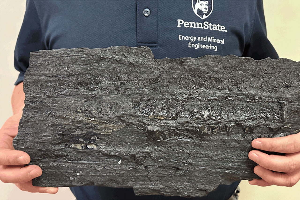 A Penn State researcher holds a large piece of coal.