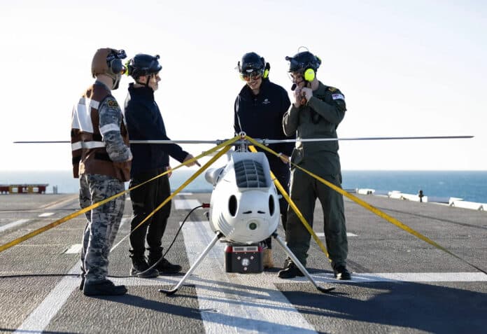 S100 crew from 822X Squadron and Defence Science and Technology Group personnel discuss the S100 bathymetric LiDAR sensor trials on the flight deck of HMAS Adelaide during Exercise Sea Raider.