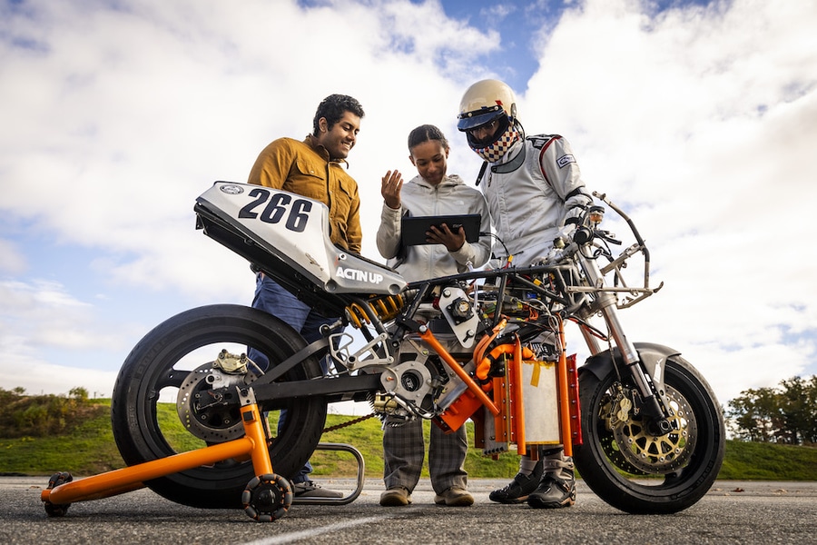 Caption:Using an on-board logging computer, Electric Vehicle Team members (from left to right:) Anand John, Rachel Mohammed, and Aditya Mehrotra check data on the bike’s performance, battery levels, and hydrogen tank levels to calculate the range of the vehicle.