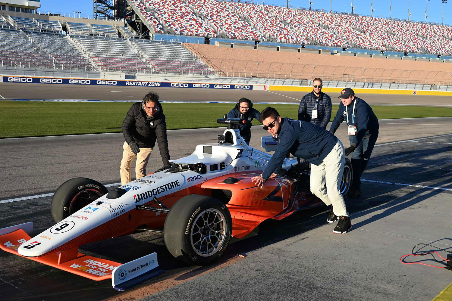 Members of the Cavalier Autonomous Racing team move their Indy car into position for a high-speed, driverless run.