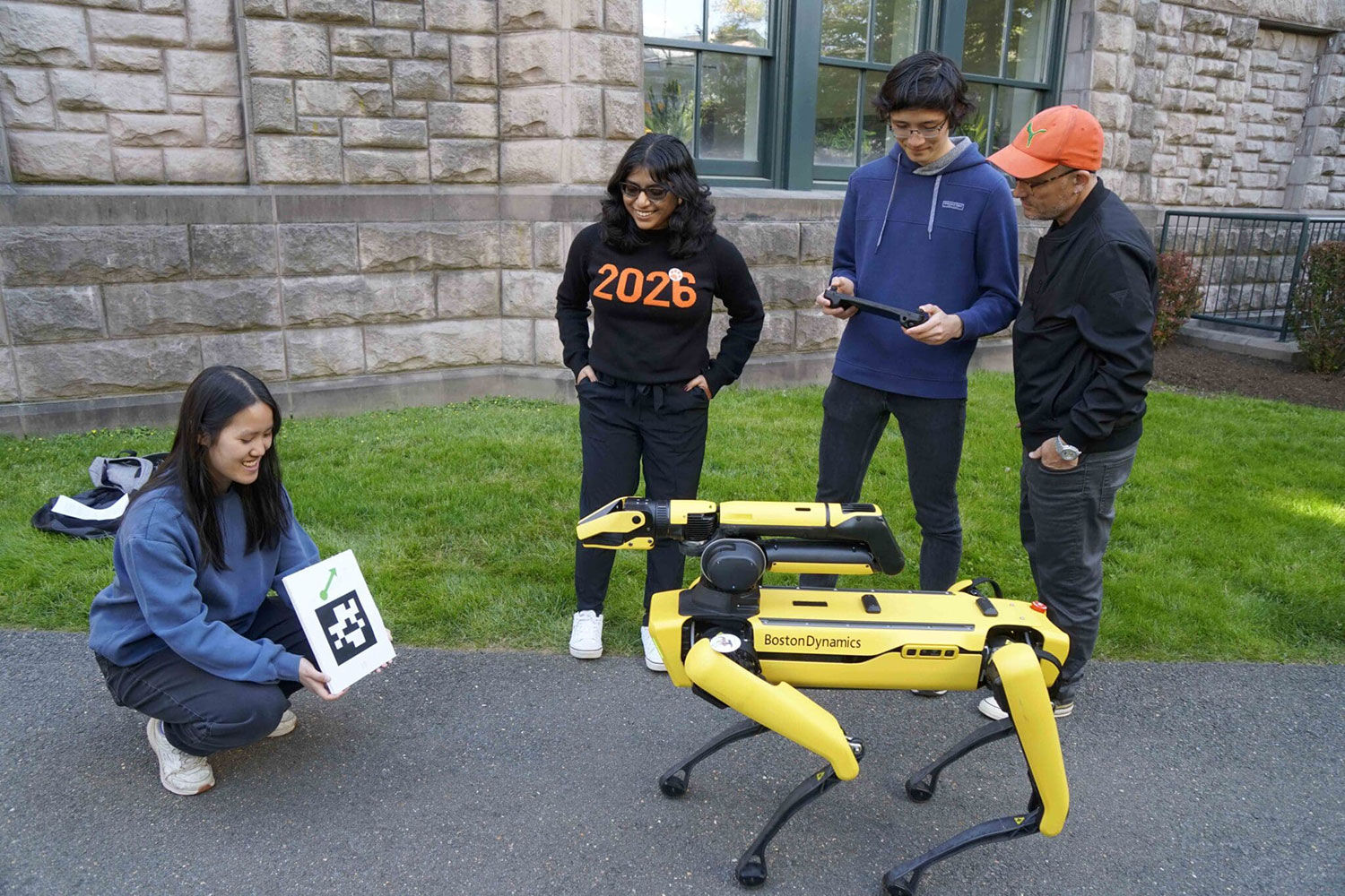 SPOT, a Boston Dynamics robot, performs tasks in response to QR codes. Vivian Chen ’25 holds the code, while Vasumathi Venkat ’25, Aaron Serianni ’25 and Prof. Alexander Glaser observe.